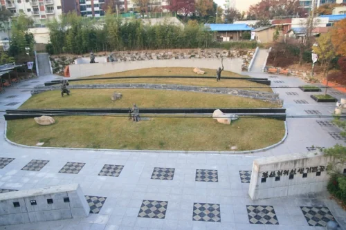 돌담 사이 계단식 잔디 마당과 인물 조형물