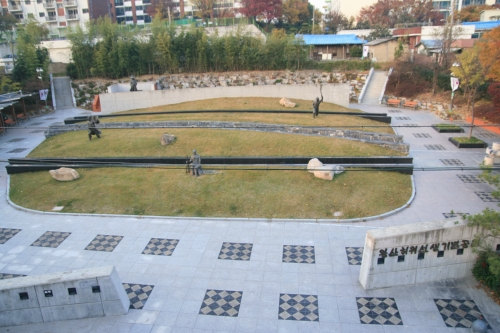 돌담 사이 계단식 잔디 마당과 인물 조형물